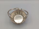 a silver plated basket with a handle on a table