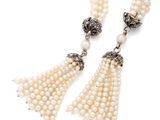 a close up of a necklace with pearls and a tassel