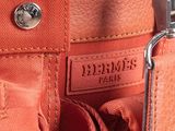 an orange leather bag with a metal handle and a name tag on it