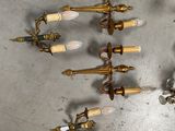six antique brass wall sconces with white candles on a gray surface