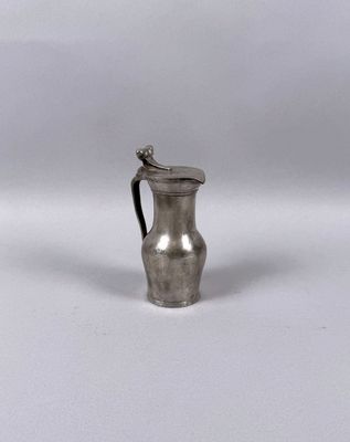 an antique silver plated pitcher with a handle on a white surface