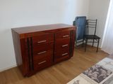 a dresser in the corner of a room with a chair