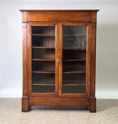 une bibliothèque ancienne en chêne avec des portes vitrées et des étagères