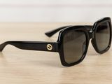 black gucci sunglasses on a wooden table with a white background