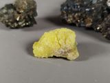 a small piece of yellow rock next to a smaller piece of black rock