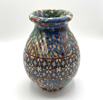 un vase bleu et brun posé sur une surface blanche