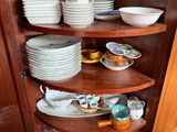 many plates and cups on the corner of a cabinet