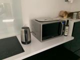 un micro-ondes et une cafetière posés sur le plan de travail de la cuisine