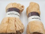 deux rouleaux de couvertures marron posés sur une surface blanche