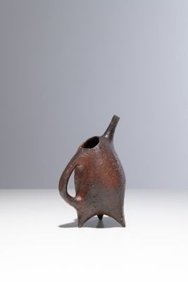 un petit vase brun posé sur une surface blanche