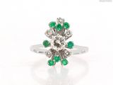 une image représentant une bague ornée d'une fleur en diamants et émeraudes sur fond blanc
