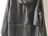 the under armour jacket is hanging on a hanger on a wall