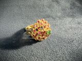 a close up of a gold ring with pink and green stones