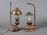 une paire de lampes à huile anciennes en laiton, posées sur des socles en bois, sur fond gris