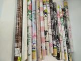 many rolls of fabric on a shelf next to each other