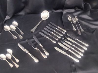 a lot of silverware on a table with a black cloth