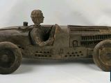 antique cast iron model of a race car with a man in the driver ' s seat