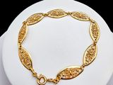 a close up of a gold bracelet on a white plate