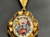 a gold pendant with a picture of flowers on it