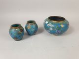 three pieces of blue and gold vases sitting on a white surface
