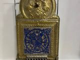 une horloge dorée et bleue exposée sur une surface blanche