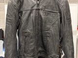 a black leather jacket hanging on a hanger in front of a wall