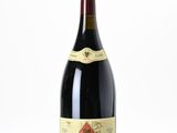 une photo d'une bouteille de vin rouge posée sur une surface blanche