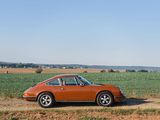 an orange car parked on a dirt road next to a field