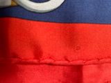 the back of a red and blue jacket with a white ring on it