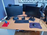 a computer desk with three monitors, a keyboard, mouse, and a mouse pad