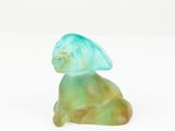 a glass figurine of a cat sitting on a white surface