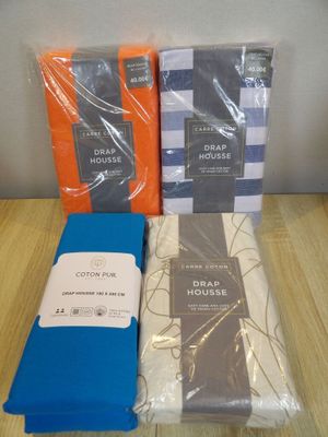 three boxes of bed sheets and a pillow on a wooden table
