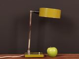 a green apple next to a yellow lamp on a wooden table