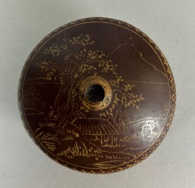 a brown vase with a painting on it sitting on a table