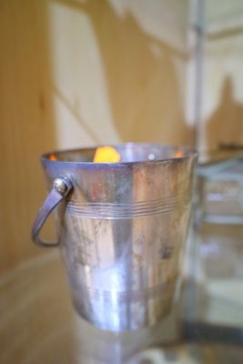 un seau en argent posé sur une table, contenant une orange