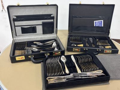 trois valises contenant de l'argenterie, posées sur une table