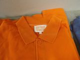 an orange polo shirt with a white tag on the collar