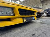 a yellow car parked in a garage with other cars in the background