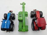 three toy tractors sitting side by side on a white surface
