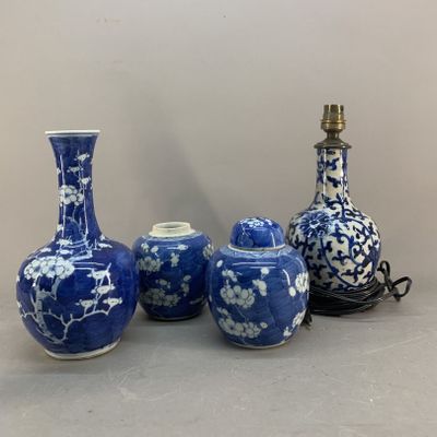 three blue and white vases and a lamp on a table