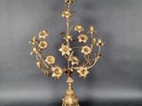 an antique brass candelab with flowers and leaves on a stand