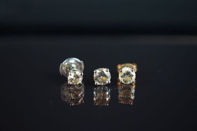 trois boucles d'oreilles en or et diamants posées sur un fond noir