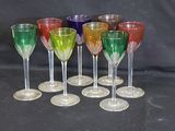 Plusieurs verres à vin de différentes couleurs sont alignés sur une surface noire