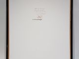 a framed photograph of a cat sitting on top of a white wall