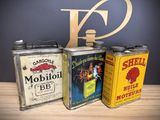 three tins of oil sitting on top of a wooden table