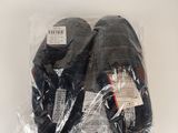 deux paires de chaussures noires sont emballées dans du plastique sur une surface blanche