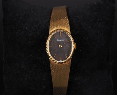 a close up of a gold wrist watch on a black cushion