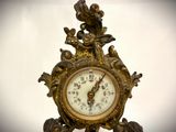 a clock that is sitting on a stand with a bird on it