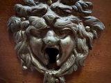 a metal sculpture of a lion head on a wooden table