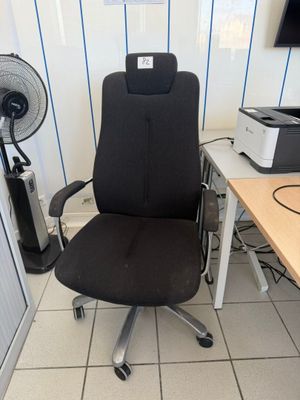 a black office chair sitting in front of a desk with a fan